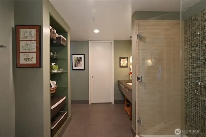 A spacious bathroom with walk-in closet thru white door.