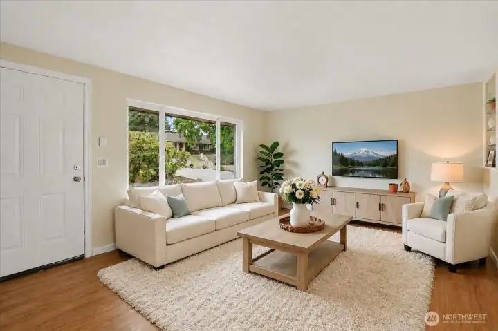 The living room of the main home welcomes you with a large picture window and luxury vinyl plank flooring.