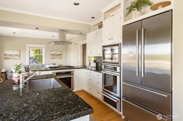 Chef's kitchen includes two electric ovens plus warming shelf - family room in background