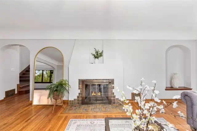 Wood burning fireplace surrounded by gorgeous arches and original hardwood floors