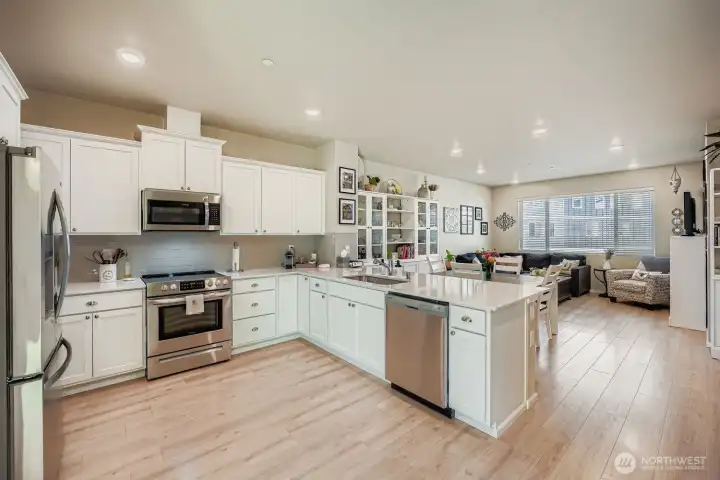 Spacious kitchen features crisp white counters, stainless appliances and bar seating.
