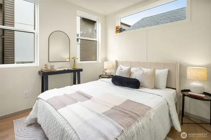 Bright and inviting guest suite or secondary bedroom with large windows and a clean, modern aesthetic.