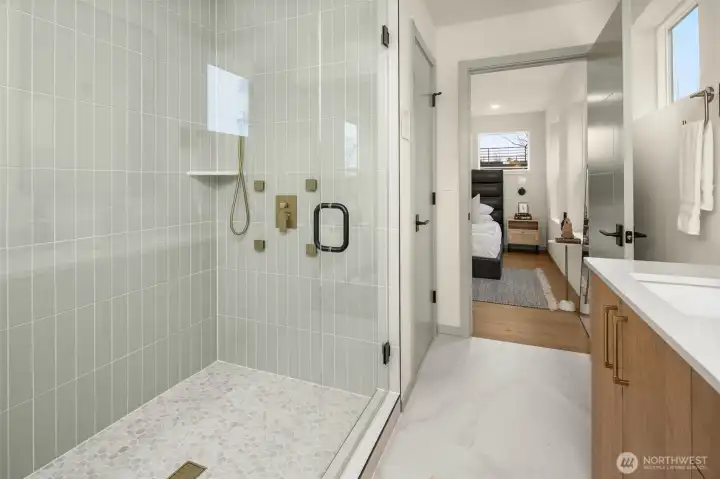 Spa-inspired primary bathroom featuring a large walk-in shower with vertical designer tile and a frameless glass door.