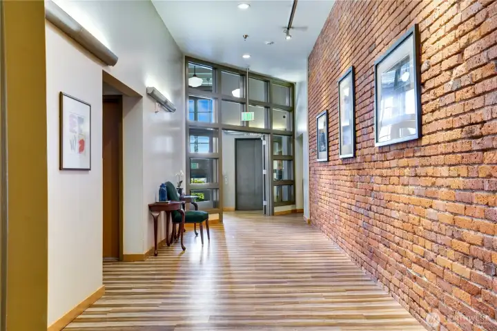 Step into the secure lobby where exposed brick, metal accents, weathered wood, and a neutral palette define classic industrial style. The elevator ahead makes coming and going effortless—let’s head upstairs!