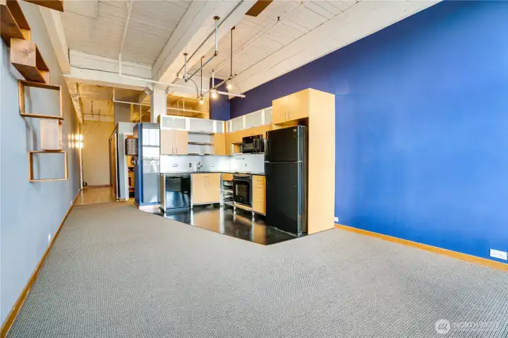 The living area flows seamlessly into a kitchen thoughtfully designed with ample cabinetry, open shelving, and pull-out drawers ideal for pots and pans—delivering impressive efficiency for everyday living.