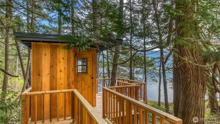 The adorable treehouse has cedar siding and metal roof to match the house.