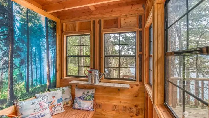 Mini studio treehouse has 5 operable windows to bring in views, sea breezes nature sounds. Bench has a roll-up bench for naps and a clever mural backdrop. It was designed as a playhouse for owner's grandchildren. Underneath the rug is a hatch with ladder to sandbox below. Owner has used for zoom calls. No electric service.