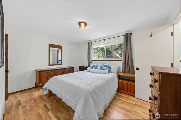 The wood floors extend into the primary bedroom.  Window looks out to the backyard.