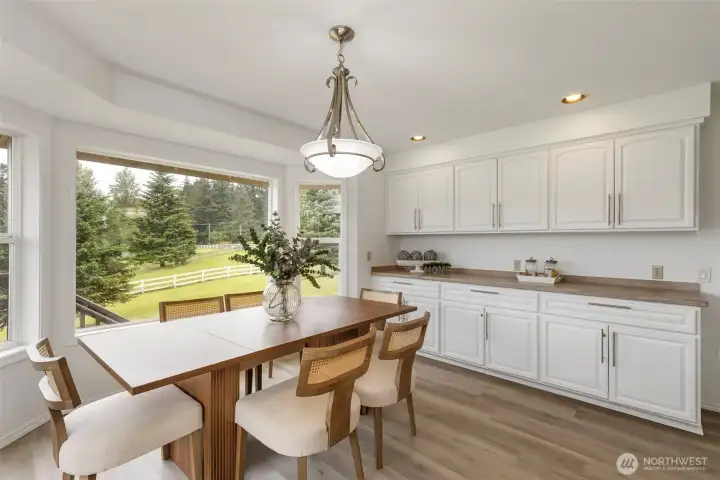 Bright dining area with oversized windows, peaceful acreage views, and elegant built-in cabinetry offering beautiful storage and refined everyday function.
