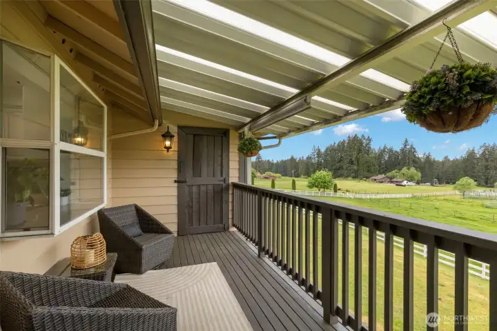 Private covered balcony overlooking lush pastures and tree-lined grounds, creating a serene outdoor lounge with elevated views, and enjoying luxury Port Orchard living.