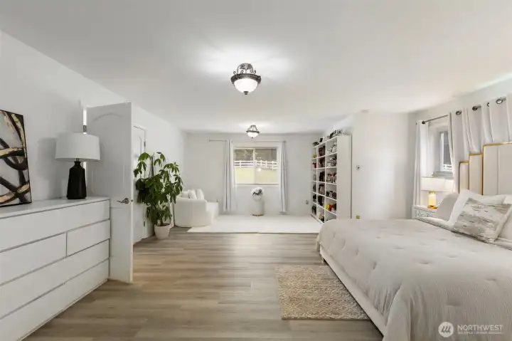 Main-level primary suite with impressive scale, peaceful window views, and a beautifully defined lounge area—offering a calm, polished retreat with room to unwind, recharge, and live comfortably.