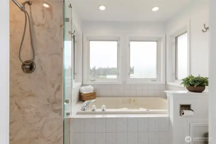 Light-filled primary bath featuring a soaking tub, glass shower, and peaceful window views—designed as a calm, spa-inspired retreat.