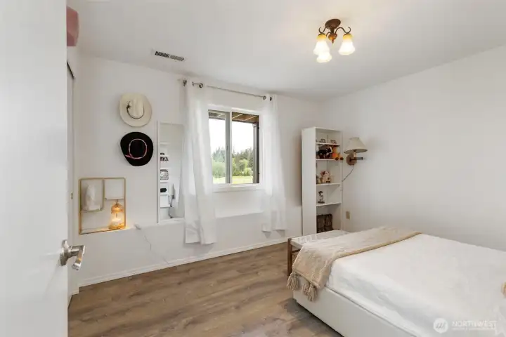 Downstairs second bedroom offers comfortable size, natural light, and peaceful window views.