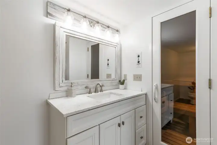 Downstairs bath with bright vanity and private sauna entry, adding a spa-inspired touch of comfort, wellness, and everyday luxury.