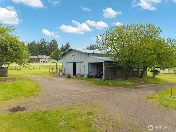 Versatile equestrian barn featuring 4 horse stalls, covered RV parking, a bonus room, half bathroom, and easy access to open grounds—designed for horses, storage, equipment, and acreage living.