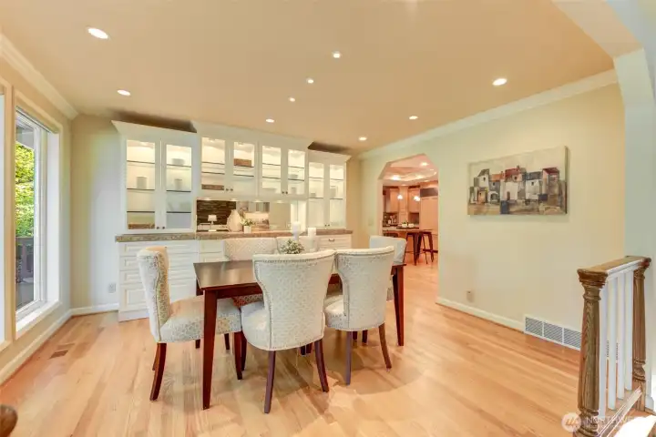 Dedicated dining area with custom built-ins, illuminated display cabinetry, recessed lighting, hardwood floors, and easy access to the beautifully remodeled kitchen.