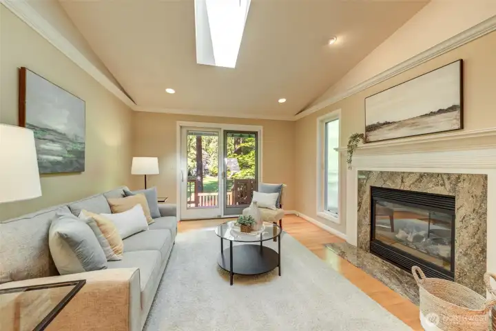 Comfortable family area just off the kitchen with fireplace, a skylight overhead, large window, and direct access to the back deck for easy indoor-outdoor living.