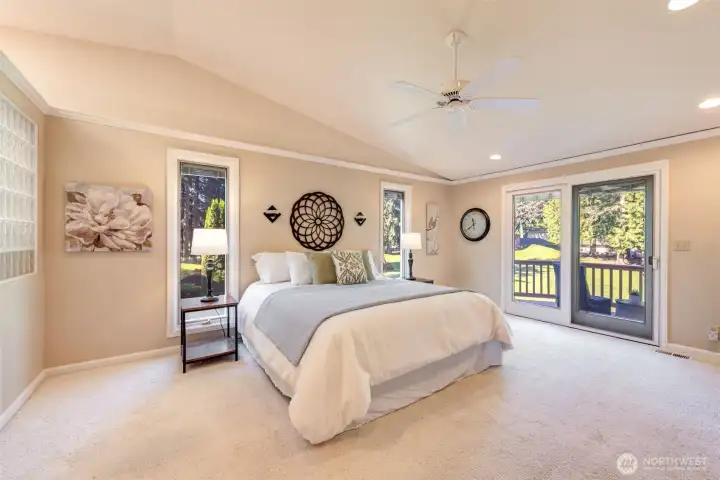 Spacious primary suite with vaulted ceilings, ceiling fan, peaceful golf course views, and private deck access for a quiet morning retreat.