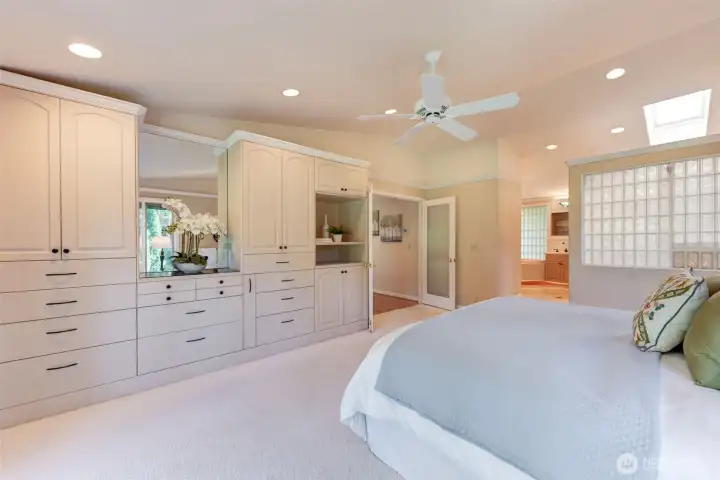 Back into the primary bedroom, it features custom built-ins, skylight, recessed lighting, and a bright, airy layout that flows into the en-suite bath.