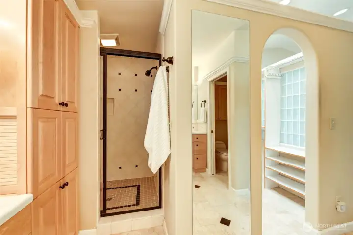 Primary en-suite features additional built-in storage, a tiled walk-in shower, full-length mirror, and direct access to the spacious walk-in closet.