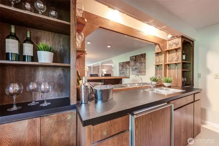 Wet bar with sink, beverage fridge, display shelving, and built-in storage designed for effortless entertaining.