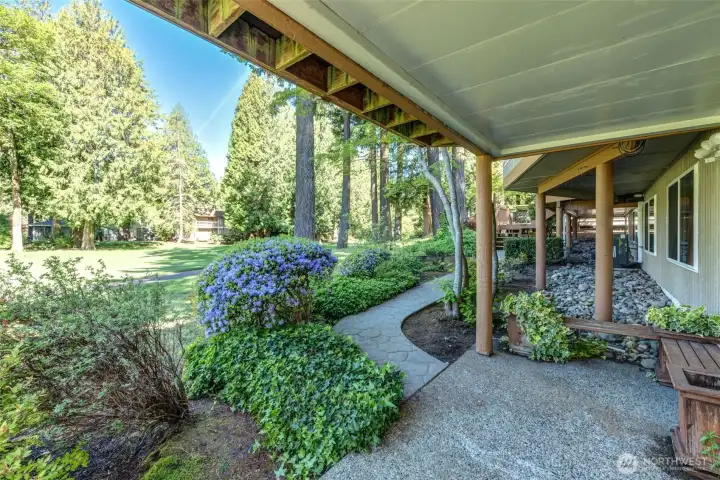 Covered lower patio with landscaped pathways connecting the backyard, upper decks, and front entry for easy flow throughout the property.