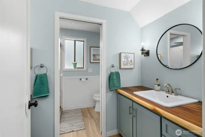 Upstairs bath features facing vanities, each with custom crafted wood counters and updated styling, and a shower beyond the pocket door