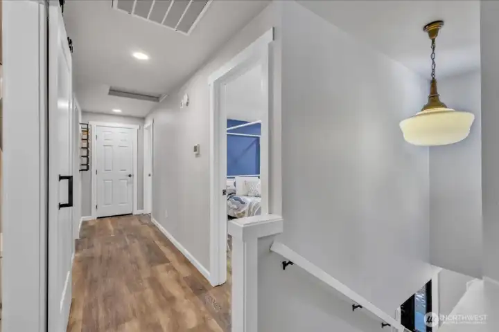 The beautiful LVP flooring, white trim and white doors are carried upstairs.