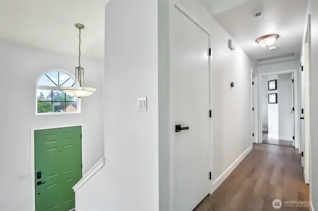 Upstairs hallway with modern light fixtures and updated doors. Arched window above front entry adds extra natural light.
