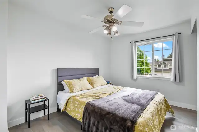 Comfortable secondary bedroom with ceiling fan, large window, and laminate flooring.