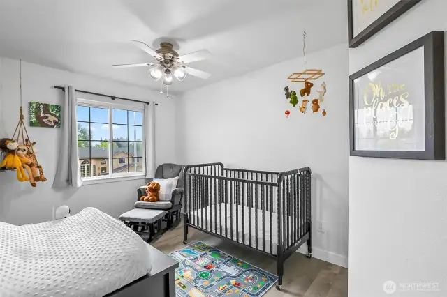 Bright third bedroom with ceiling fan and large window. Versatile layout perfect for nursery, guest room, or office.