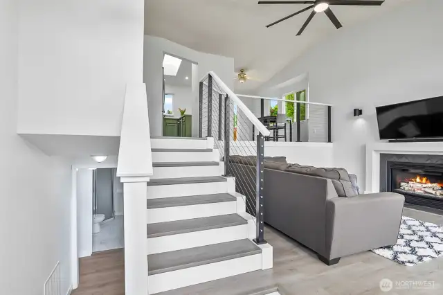 Split-level layout with open railing, modern ceiling fan, and easy flow from living to kitchen and dining areas.