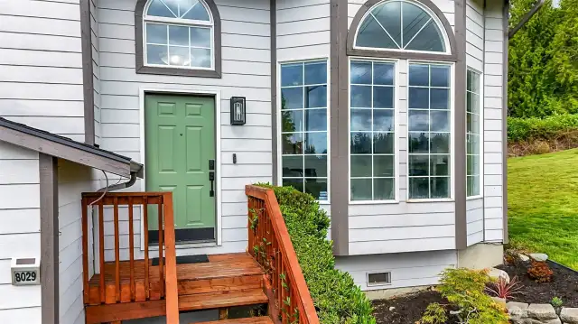 Front entry stairs, modern lighting, and a statement green door framed by tall windows.