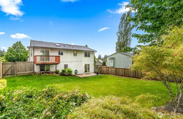 Fully fenced backyard with deck, patio, and lush lawn. Ample space for play, pets, and outdoor entertaining.