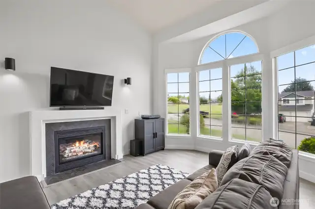 Large arched windows with wood-wrapped frames provide abundant natural light and views of the landscaped front yard.