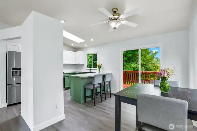 Open dining area with slider to back deck. Seamless flow into kitchen with bar seating, updated lighting, and LVP flooring.