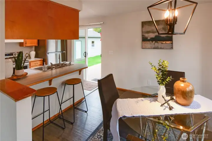 Light-filled dining area with breakfast bar and easy access to the backyard deck through sliding glass doors — perfect for everyday living and indoor-outdoor entertaining.