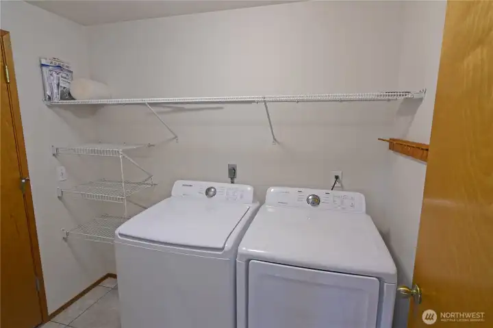 Dedicated laundry room with full-size washer and dryer plus built-in shelving for extra storage and organization.
