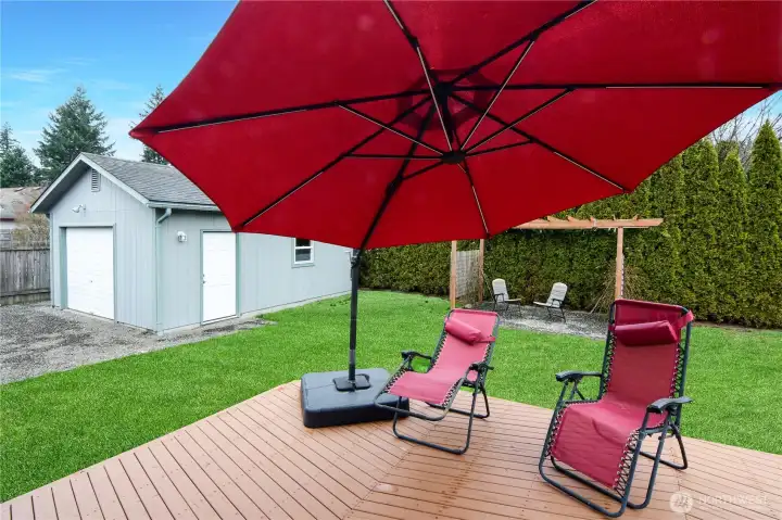 Spacious backyard with entertaining deck, lush lawn, and detached shop/garage — ideal for hobbies, storage, or extra workspace, all in a private setting.