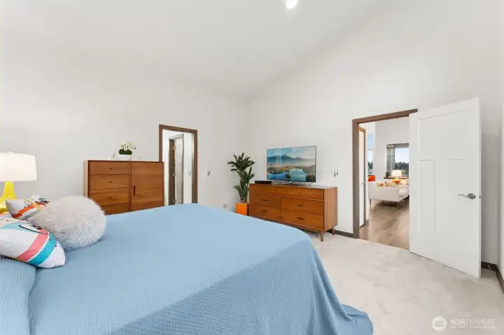 Spacious primary bedroom with vaulted ceilings, a walk-in closet, and an attached ensuite bath.