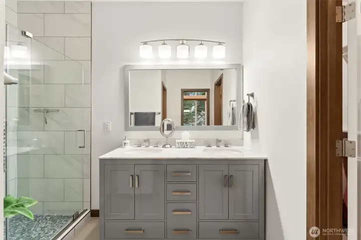 Fully updated primary bathroom featuring a tiled shower surround, glass enclosure, and new fixtures.