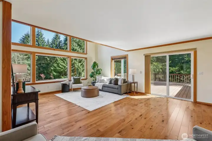 From Living Room looking out to Deck, surrounded by trees and flowers.