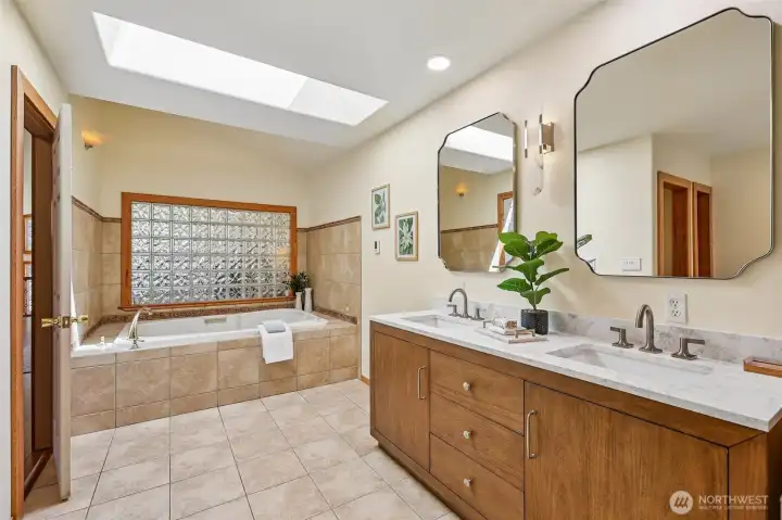 View of jetted tub, upgraded double vanity and skylight.