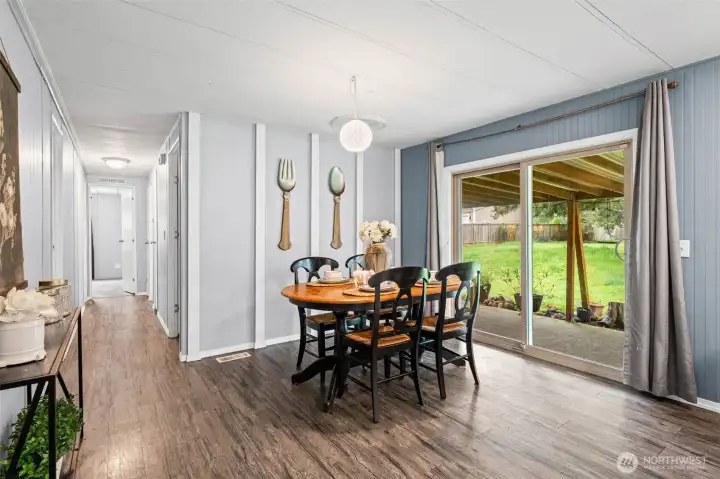 Informal dining area  and a peak of the covered back patio.   Hallway leads to the primary with en-suite, full guest bath, and 2 additional guest bedrooms.