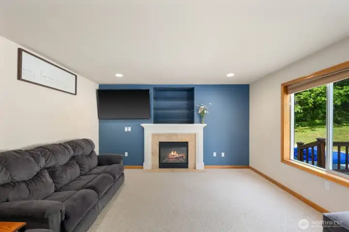 Main floor family room with fireplace, recessed lighting, and large backyard-facing windows connecting the interior to the outdoor living space.