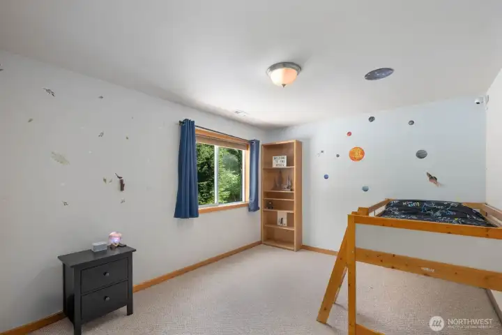Spacious secondary bedroom with large window, wooded views, and plenty of room for furniture, storage, or play space.