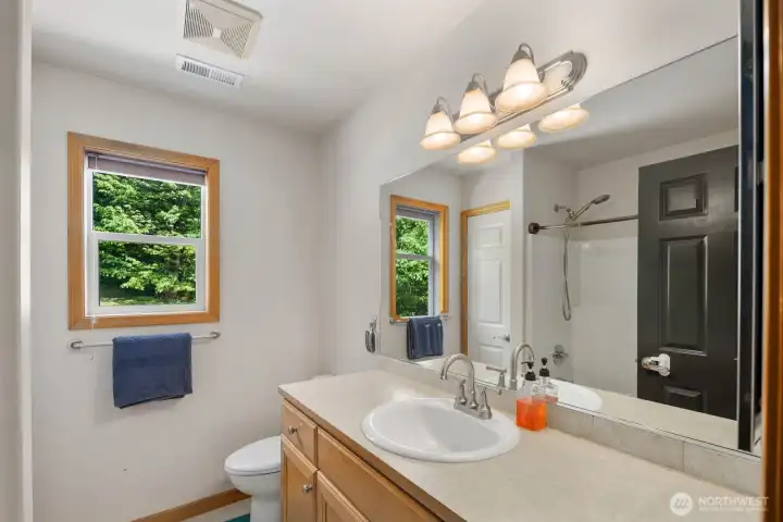 Full guest bathroom with extended vanity, natural light, and tub/shower combination.