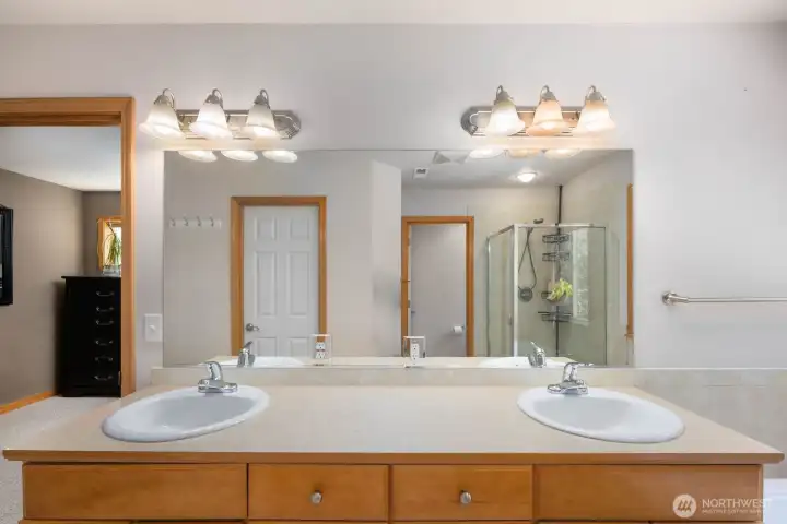 Spacious primary bathroom with dual-sink vanity, oversized mirror, and direct access to the walk-in shower and soaking tub.