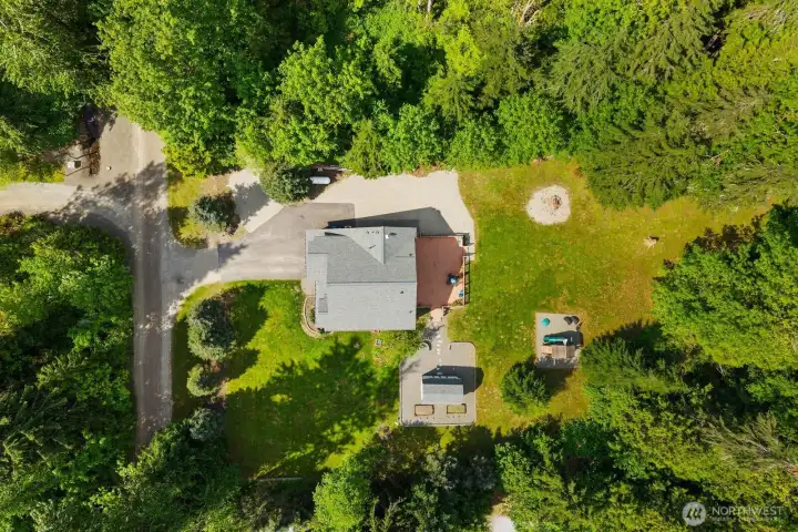 Aerial view showcasing the home’s expansive lot, circular driveway, detached shed, and surrounding privacy.