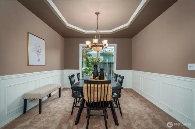 The formal dining room includes coved ceilings, wainscoting, and a large window that overlooks the beautifully landscaped backyard—a perfect setting for gatherings of any size.